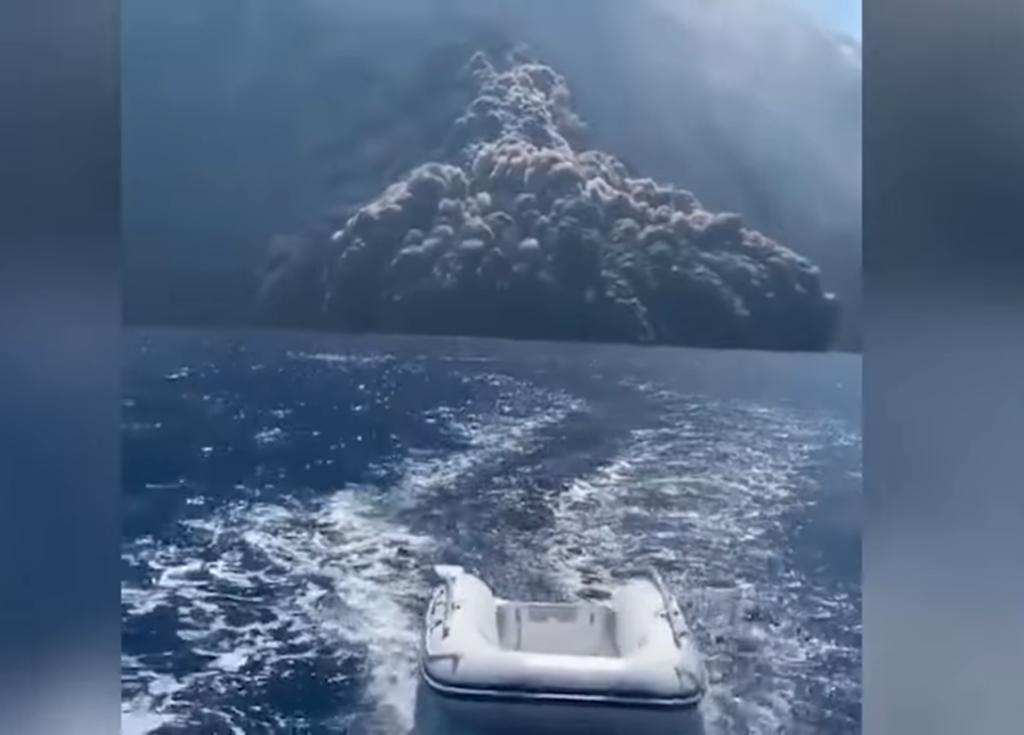 Personas huyen en una embarcación de un volcán en erupción