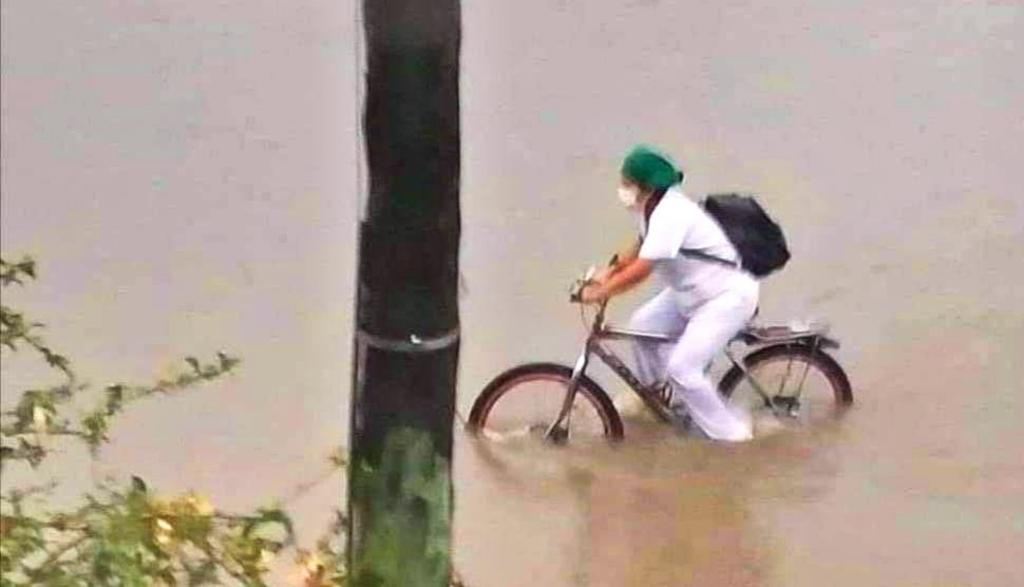 Premian a enfermera que se transportaba en bicicleta entre las calles inundadas