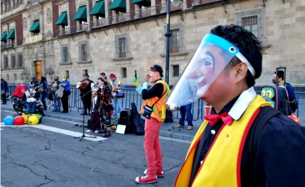 Payasos y cirqueros hacen malabares frente a Palacio Nacional