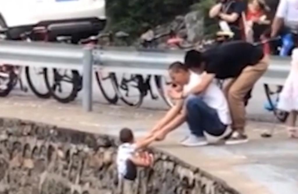 Hombre cuelga a niño de acantilado para tomarle una fotografía